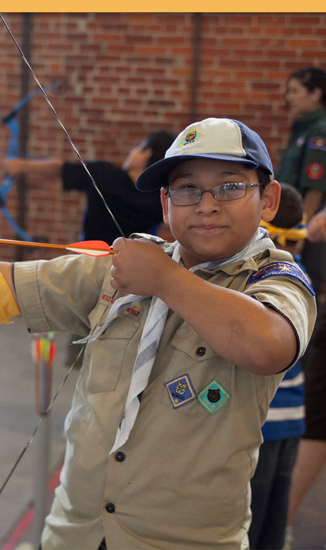 Scout drawing a bow indoors